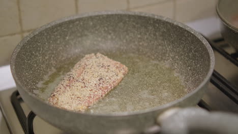 Close-Up,-Female-Hands-Putting-Piece-of-Flavoured-Salmon-Fish-Meat-in-Frying-Pan-on-Stove-at-Home-Kitchen,-Slow-Motion