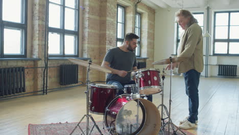 senior musician teaching young man to play drums