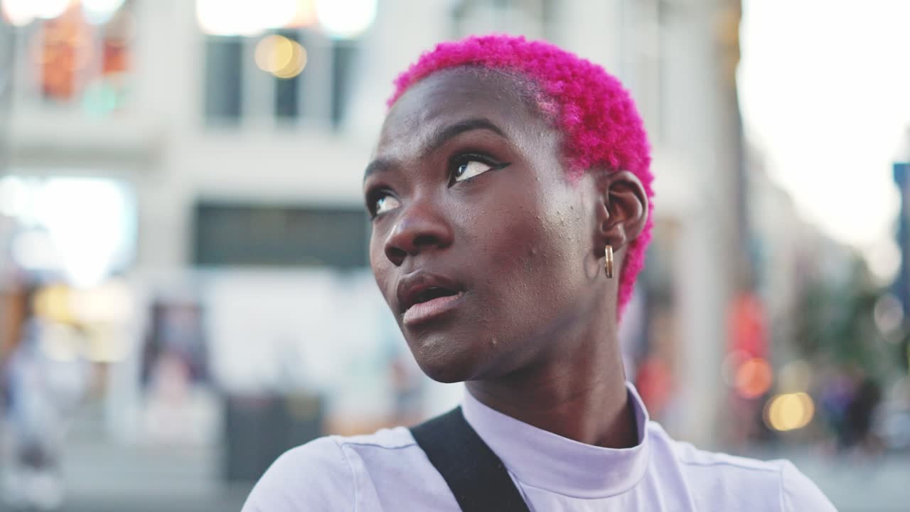 Close-up portrait of a person with vibrant pink hair in an urban setting
