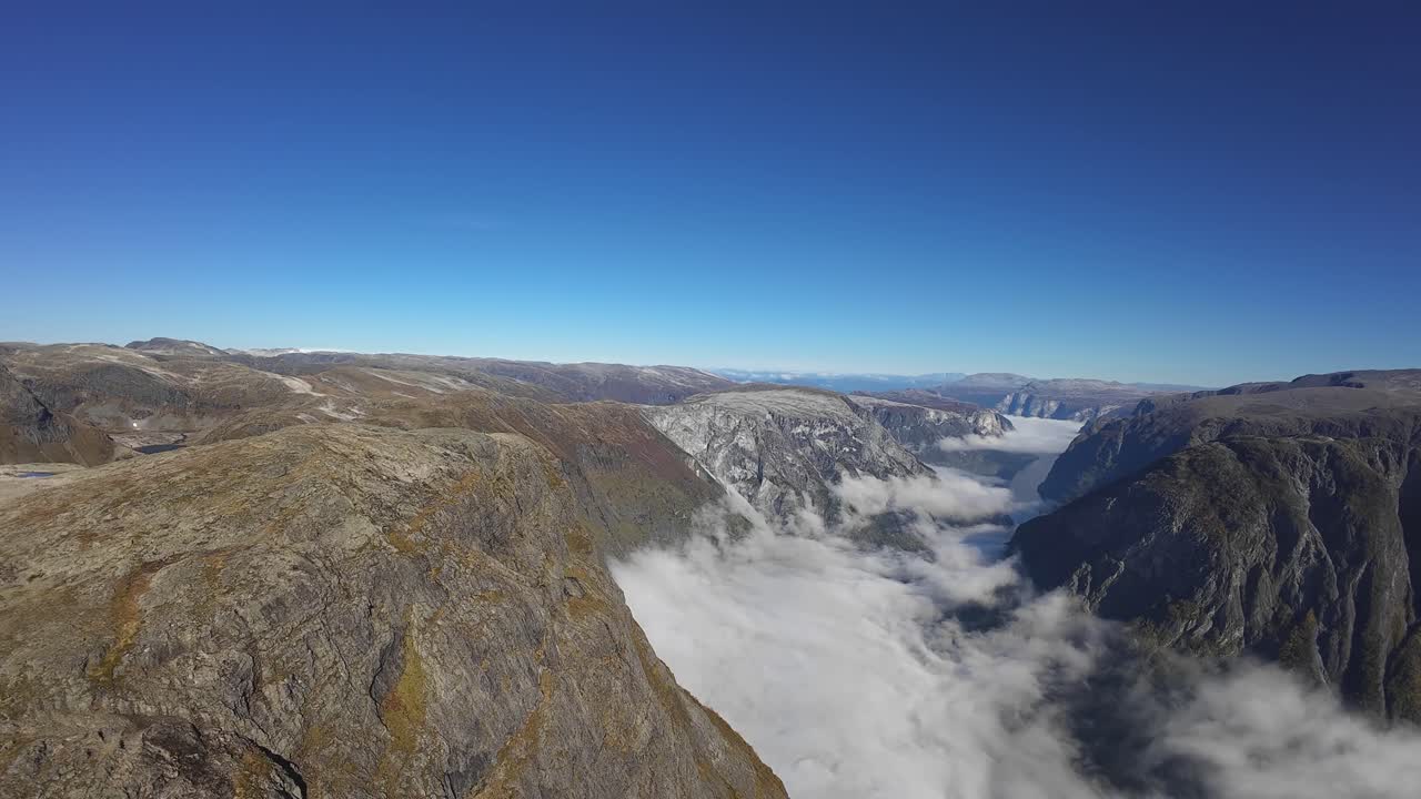 Forward aerial over Naeroyfjord, flying toward Aurlandsfjord and Breiskrednosi with Bakkanosi to the left. Sunny with cloud inversion below
