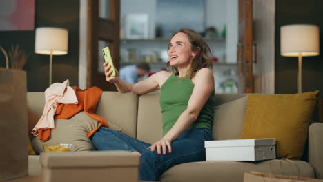 mujer feliz usando su teléfono inteligente en el sofá. adicto a las compras de gran alegría regocijándose emocionalmente