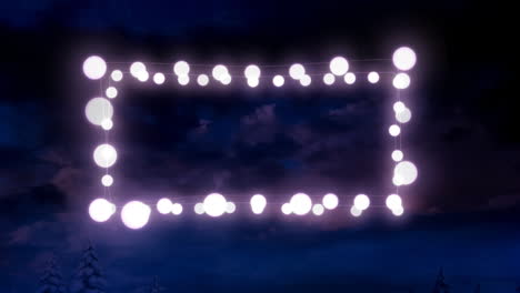 animation of fairy light frame with copy space over fir trees and winter scenery