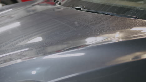 Hand-drying-car-engine-hood-with-yellow-cloth