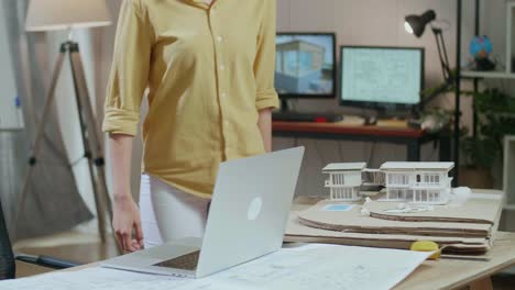 Asian Woman Engineer Walk Into The Office Before Looking At Blueprint And Typing On A Laptop