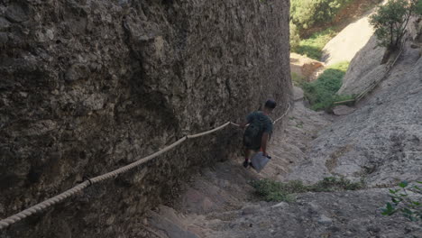 adventurous hiker descends steep stone stairs alongside majestic rock wall