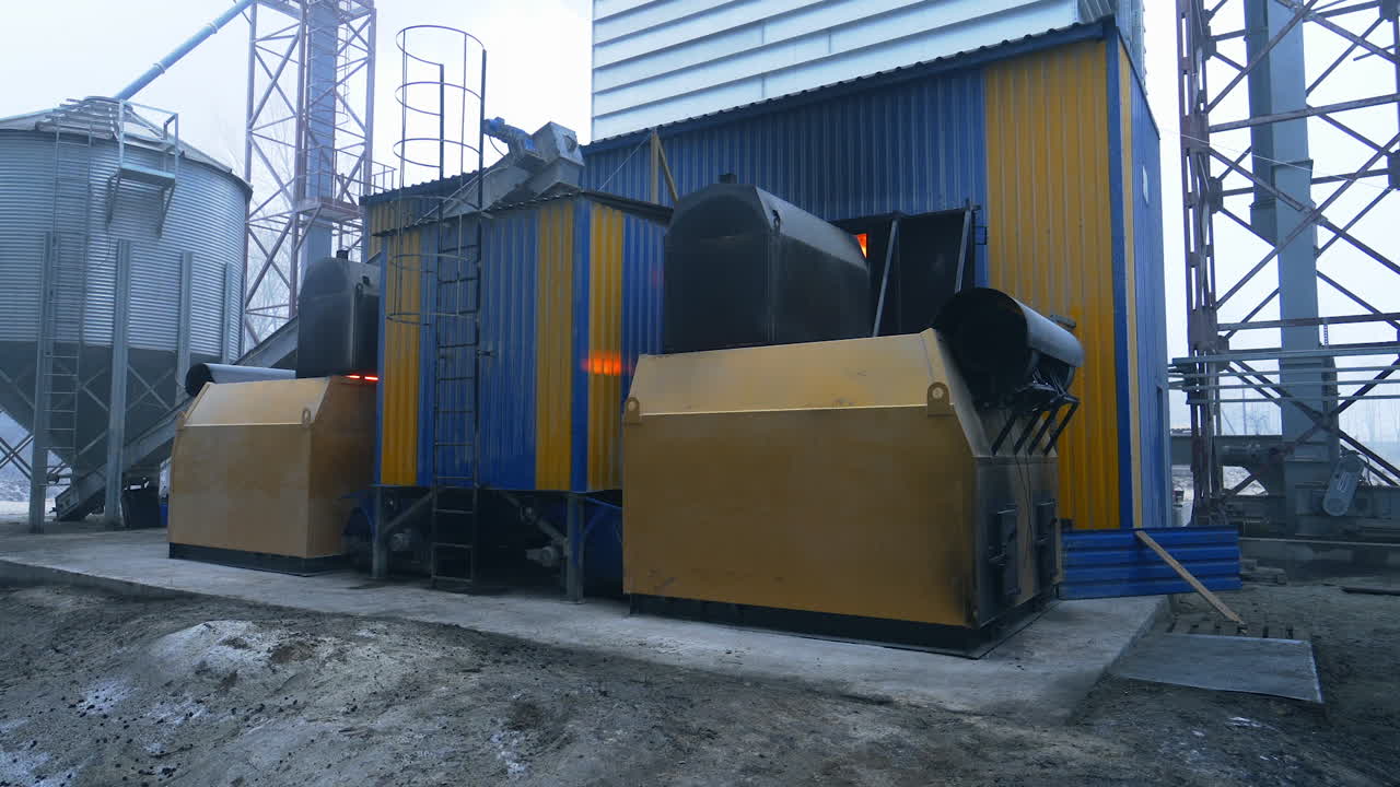 Various kinds of premises in the up-to-date agricultural granary storage. The hearth placement exterior with burning charcoal inside. Elevator structures on a foggy day.