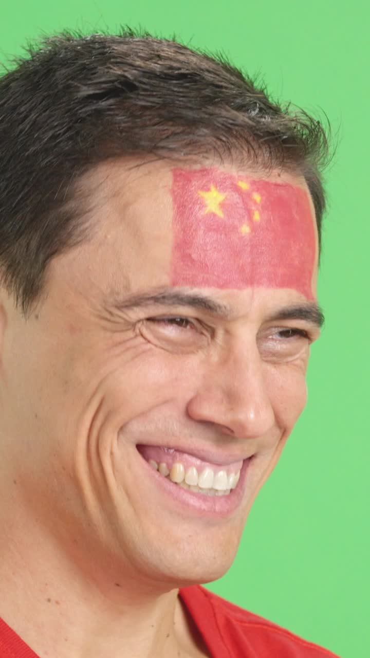 Happy man with chinese flag painted on face looking away