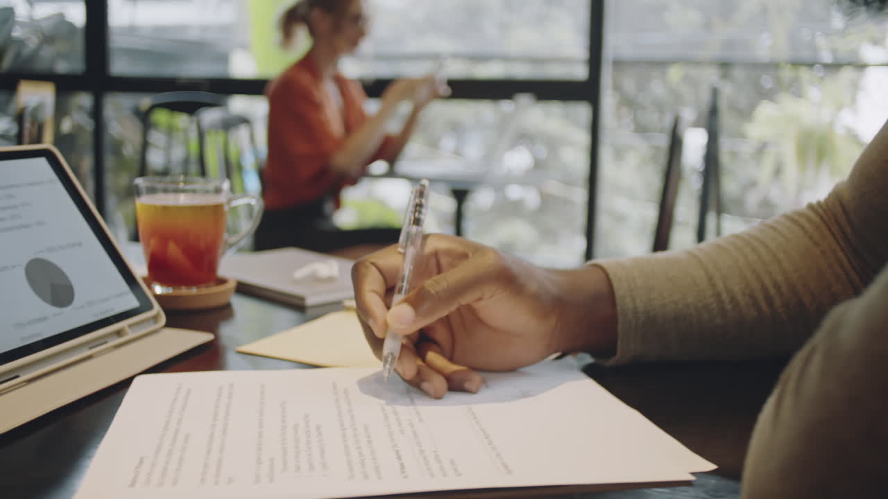 Businessman Using Tablet and Taking Notes in Cafe