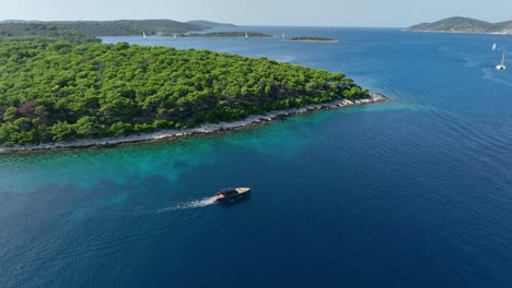 boat sailing in pakleni islands adriatic sea - aerial orbit sunny day