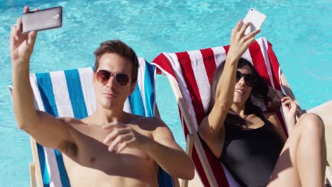 Man-and-woman-taking-self-portraits-at-pool