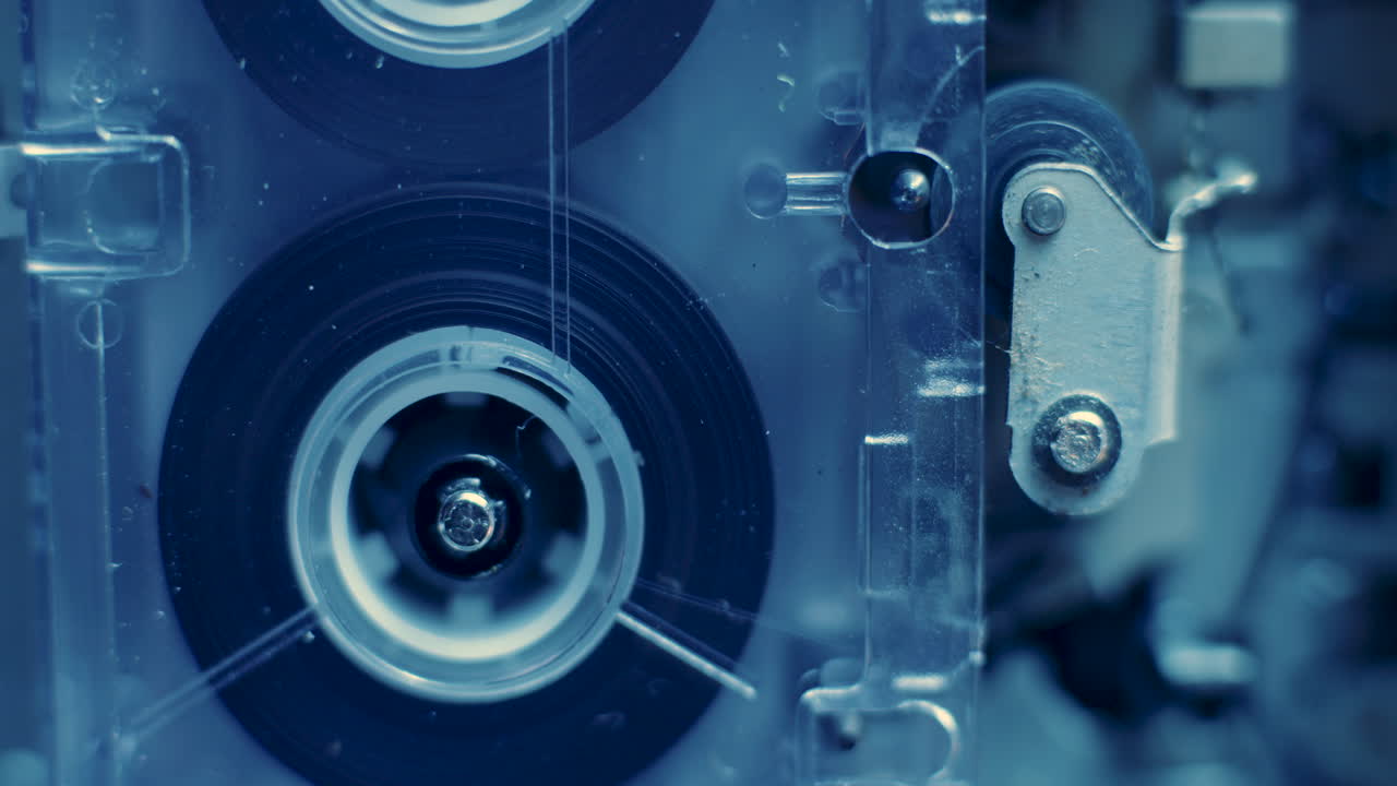 차가운 파란색 빛에 핀치 롤러가 있는 마이크로카세트 레코더의 카세트 릴