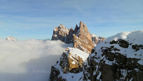 amazing aerial view of snow-covered seceda mountain peaks above vast clouds