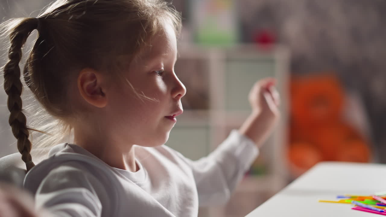 Una piccola bambina intelligente conta gli elementi sul tavolo durante il calcolo mentale.