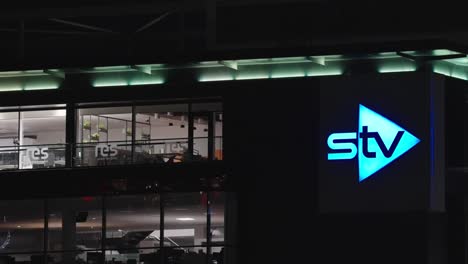 neon blue cuts through the dark, glowing logo sign, a city mark