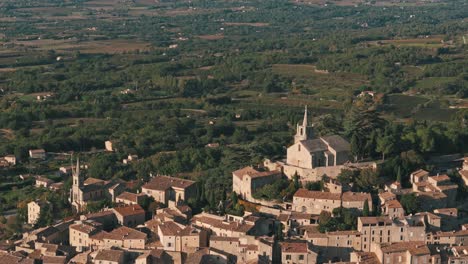 aerial retreating pan up view of bonnieux, provence, france, highlighting the village’s scenic rooftops and countryside landscape
