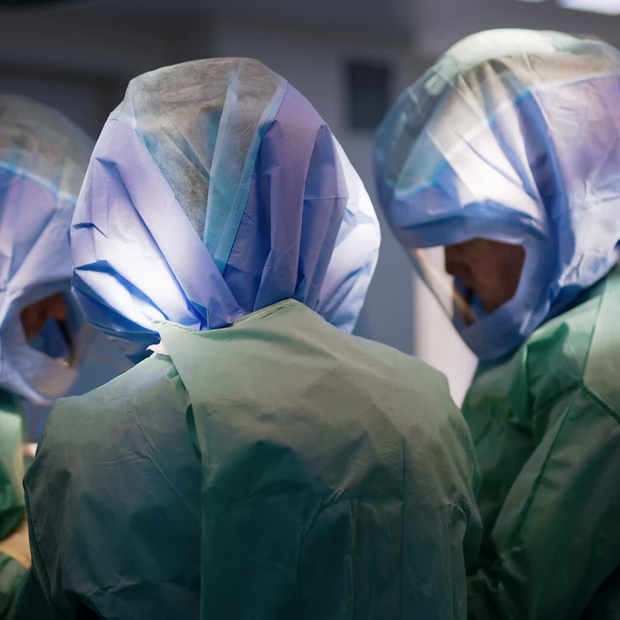 Rear view of the surgeons wearing protective helmets at operation. Trauma surgery process in modern clinics