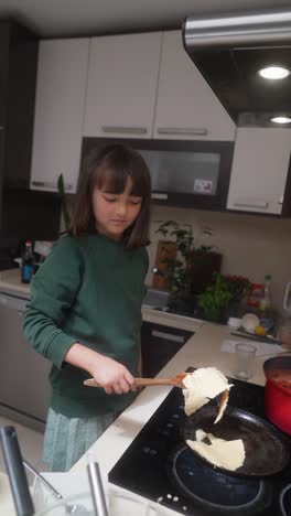 young girl cooking pancakes