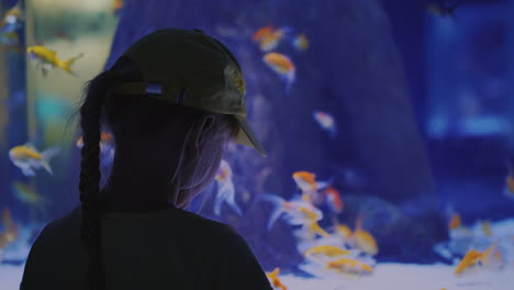 side view little girl looking at a huge aquarium with sea fishes inspiration and impressions concept