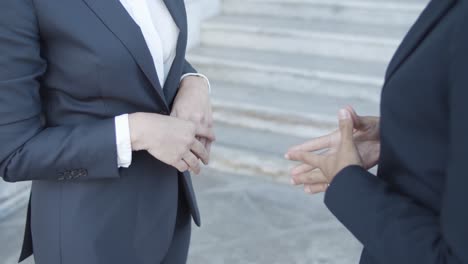 movimiento vertical de dos mujeres de negocios en trajes de pie afuera y hablando juntos