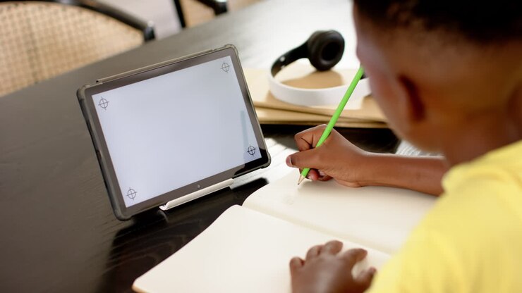 Writing in notebook, child using tablet and pencil for schoolwork at home, copy space