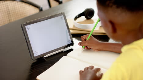 writing in notebook, child using tablet and pencil for schoolwork at home, copy space