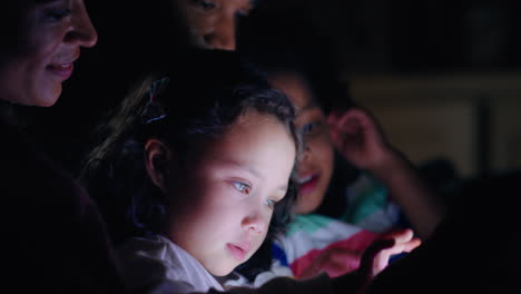 familia feliz usando una tableta con los niños madre y padre viendo a los niños jugar a juegos en la tecnología de pantalla táctil disfrutando de una noche relajante antes de acostarse