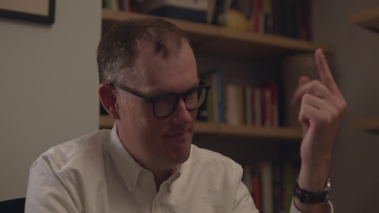A close up of a man in glasses counting to five with his fingers in different variations