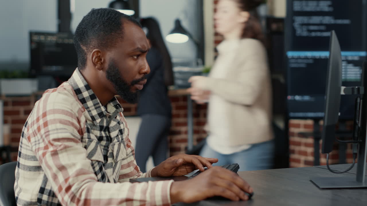 Tripod shot of african american cloud programer writing code focused looking at computer screen