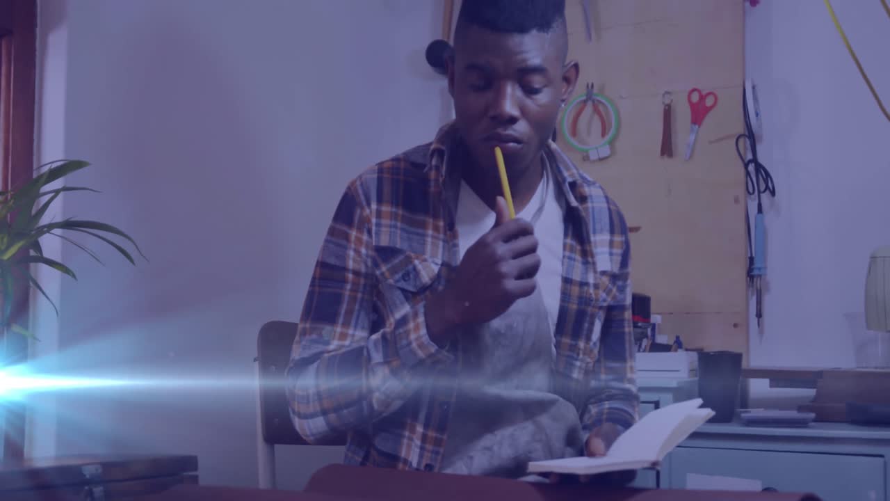 Animation of glowing light over african american man working in warehouse