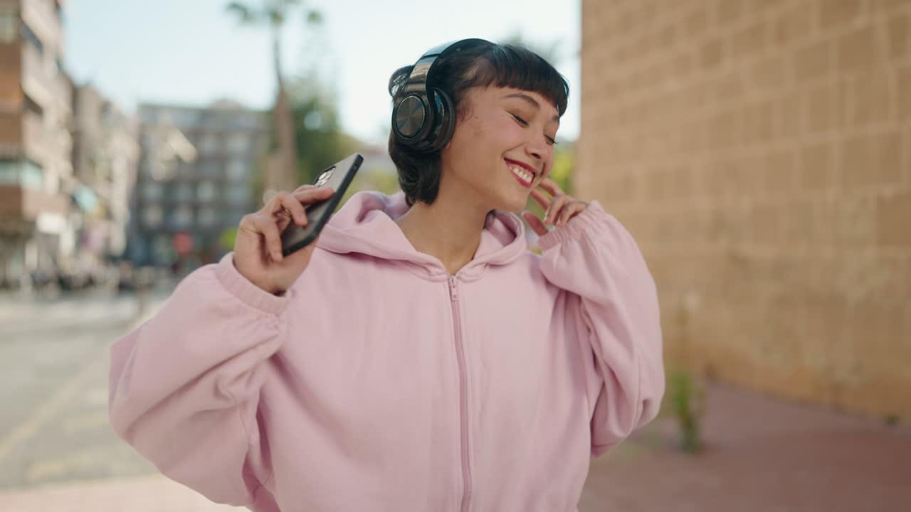 Young hispanic woman smiling confident listening to music and dancing at street