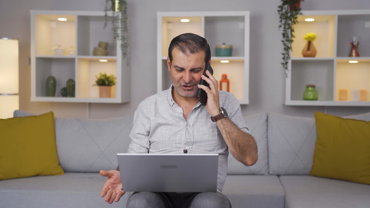 hombre usando una computadora portátil hablando nerviosamente por teléfono.