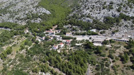 small-village-on-the-Croatian-coast-on-a-coastal-road-with-some-moving-cars,-sunny-nice-weather