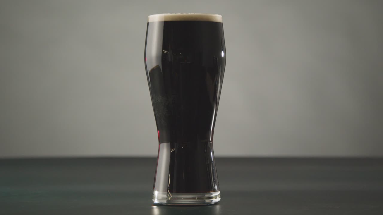 세인트 패트릭의 날 1을 축하하기 위해 스튜디오 배경에 대해 유리에 아일랜드 스타우트 파인트를 집어드는 사람