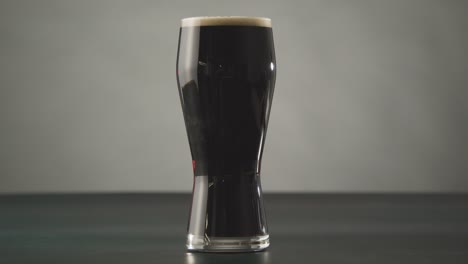 person picking up pint of irish stout in glass against studio background to celebrate st patricks day 1