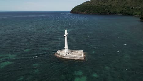 white cross monument at sunken cemetery near shore of camiguin, aerial