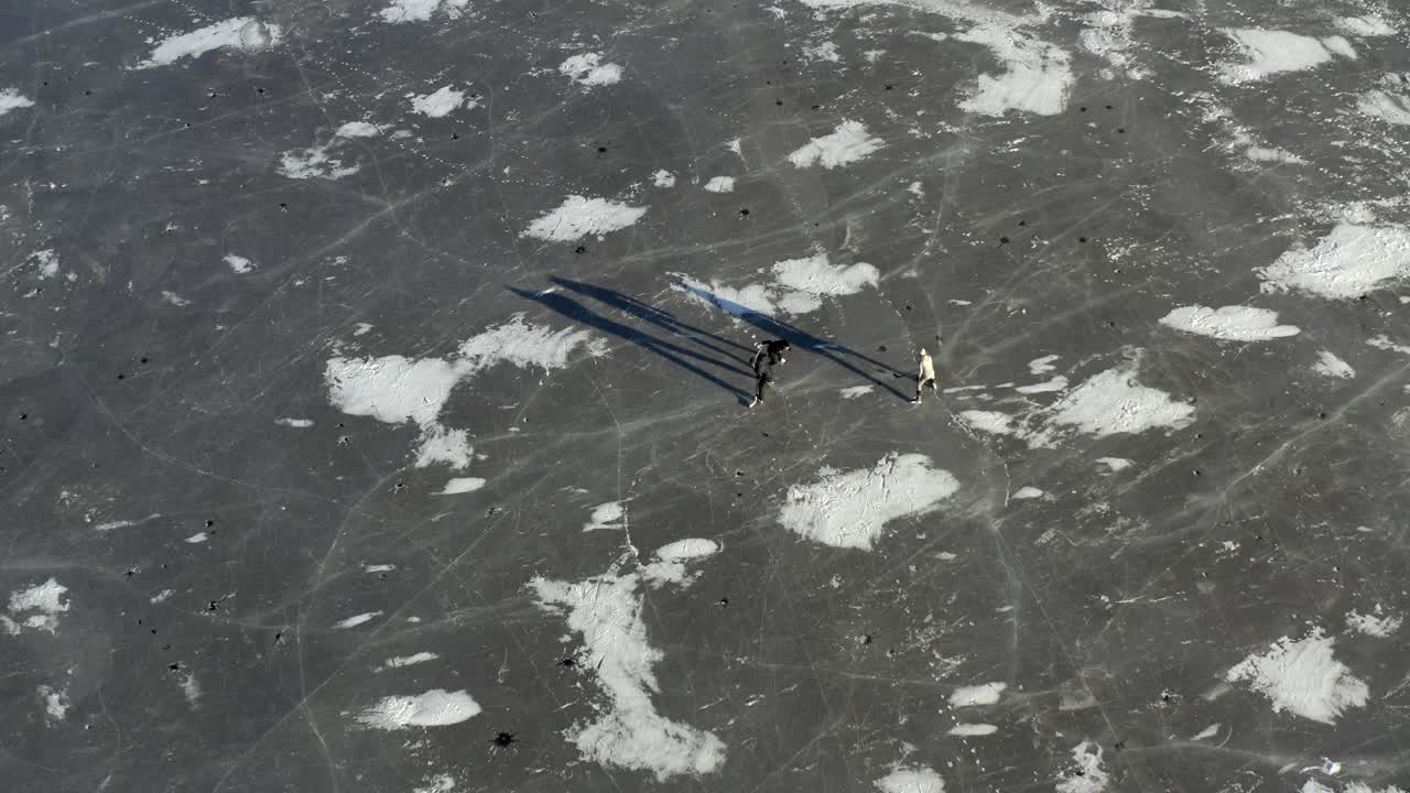 люди катаются на коньках - играют в хоккей на замерзшем озере - съемка с дрона с воздуха 4k