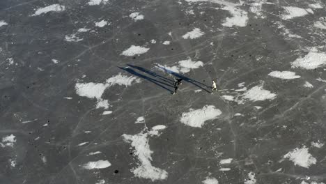 people ice skating - playing hockey on a frozen lake - aerial drone shot 4k