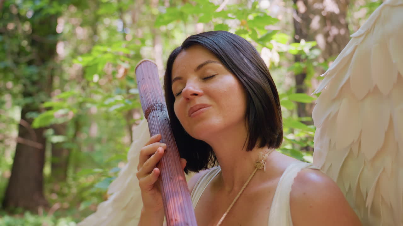 Nature lover seated in forest holding wooden staff, gently tapping it like harp while closing eyes, surrounded by green leaves and sunlight, expressing peace, and connection with natural harmony