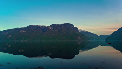 time lapse shot of cruising ship in fjord during beautiful sunrise with water reflection of mountains