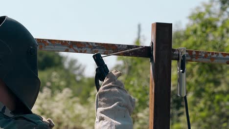 slow motion man in workwear builds fence using weld machine