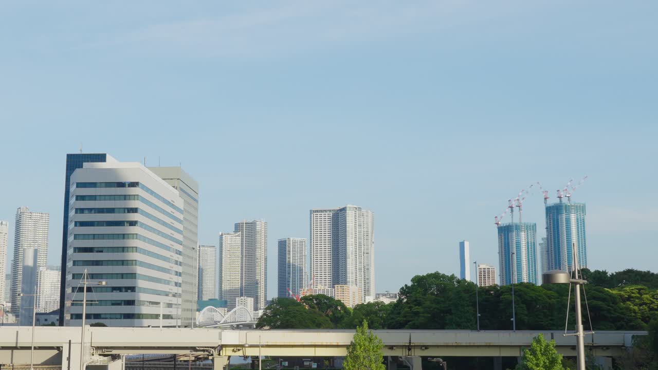 Uma vista do horizonte moderno de Tóquio com vários edifícios altos, incluindo dois em construção com guindastes