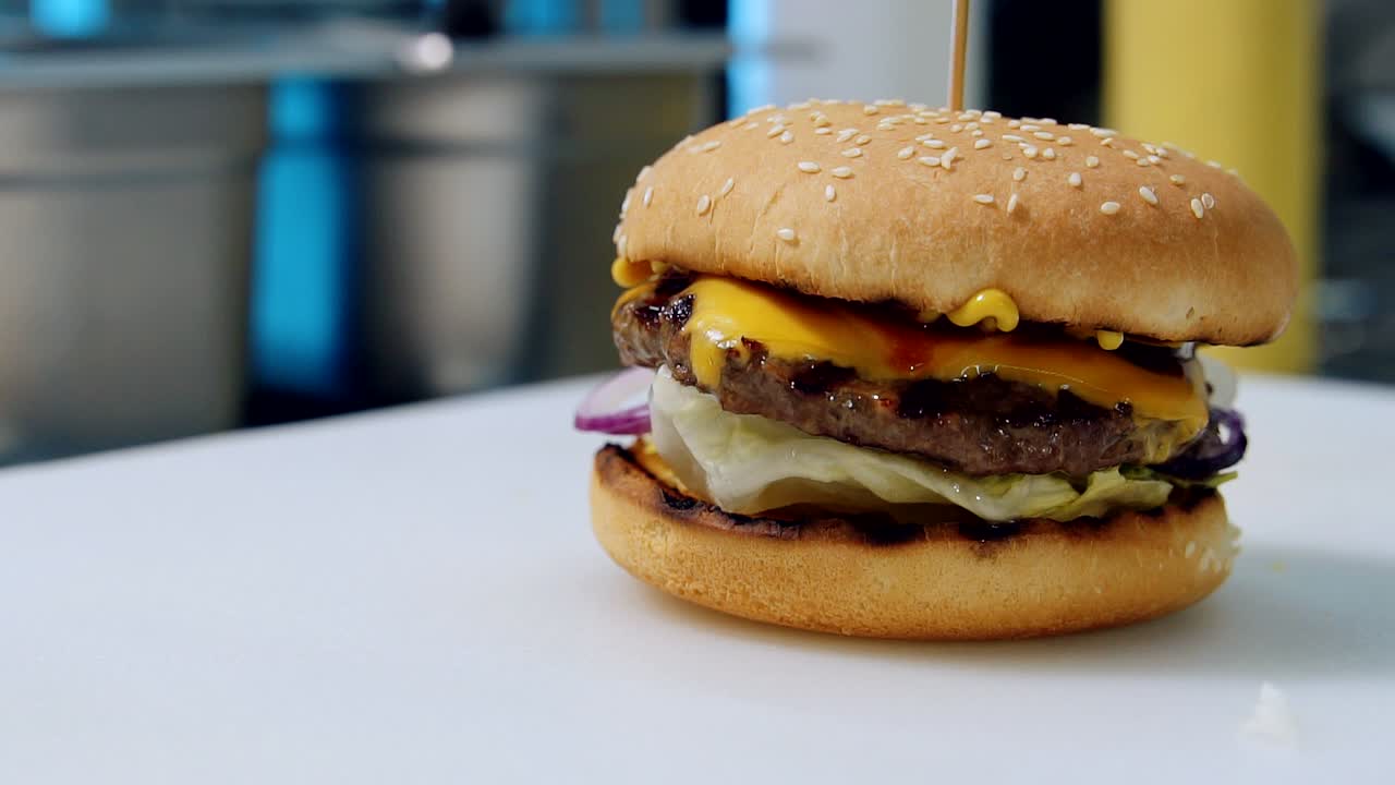 Freshly cooked burger ready to eat. Hot delicious cheeseburger with cutlet, vegetables and cheese on table in restaurant. Close-up