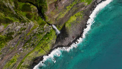 Dramatic-overhead-view-of-Veu-da-Noiva-waterfall-on-rocky-coastline,-Seixal