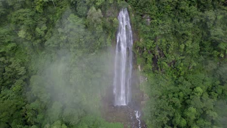 panorámica aérea a la derecha de la cascada de las lajas que fluye en un acantilado alto rodeado de densos bosques, san luis morete, costa rica