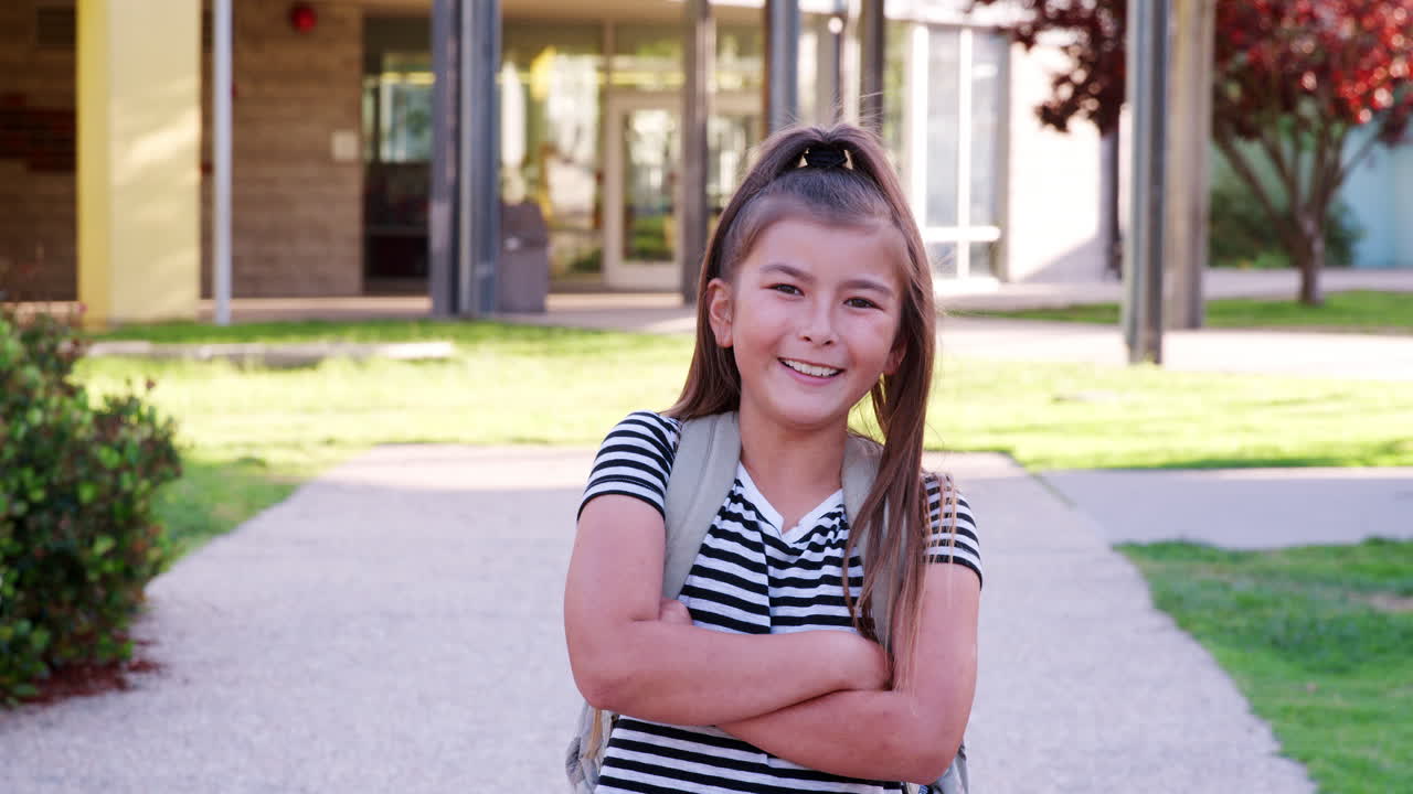 Schoolgirl walking to camera smiling, arms crossed