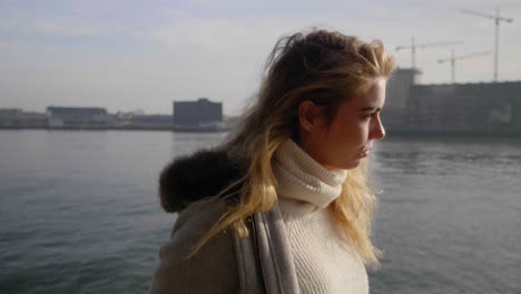 Introspective-young-woman-walks-alone-on-a-boardwalk-along-the-bay