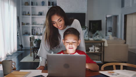 Mujer-Hispana-Ayudando-A-Su-Hijo-Mientras-Hace-Su-Tarea-Con-Una-Computadora-Portátil,-Vista-Frontal,-De-Cerca