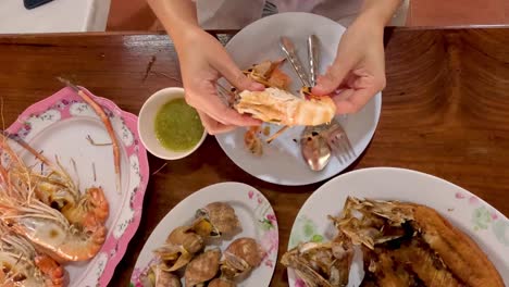 hands peeling and deveining shrimp on a plate.