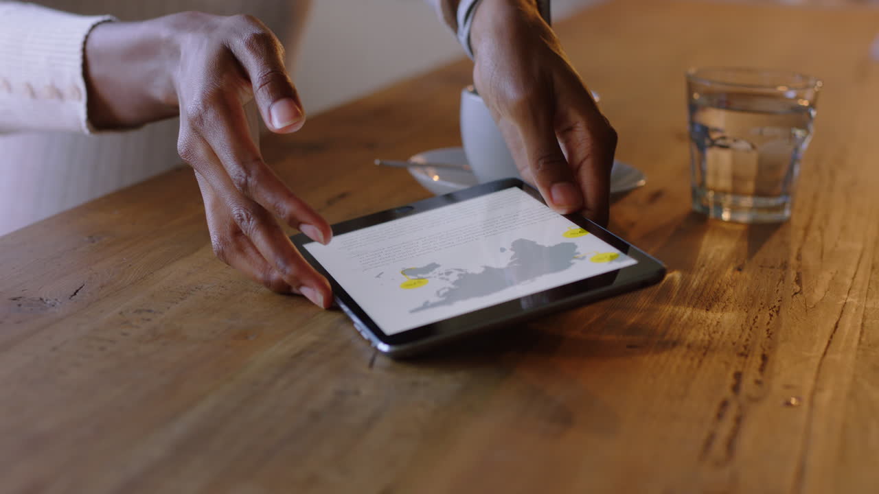 mujer de negocios afroamericana usando una tableta en un café bebiendo café navegando leyendo mensajes de correo electrónico en línea en un dispositivo de pantalla táctil disfrutando de la tecnología de comunicación móvil de cerca con las manos