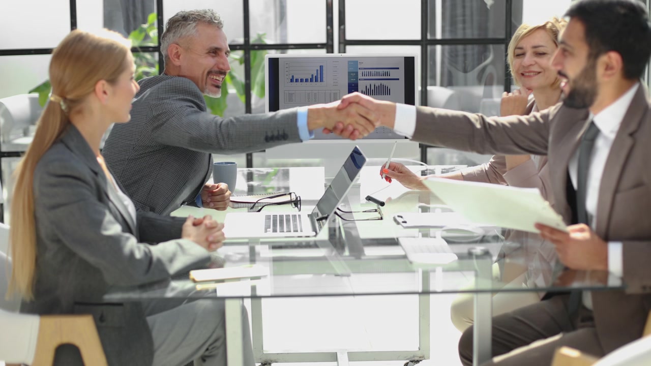 Professionisti aziendali che discutono di dati e si stringono la mano in un moderno meeting d'ufficio
